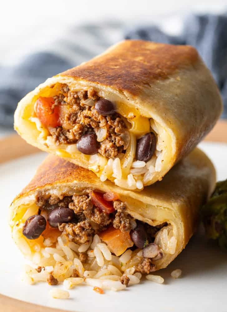 Two halves of a beef and cheese burrito stacked on top of each other.