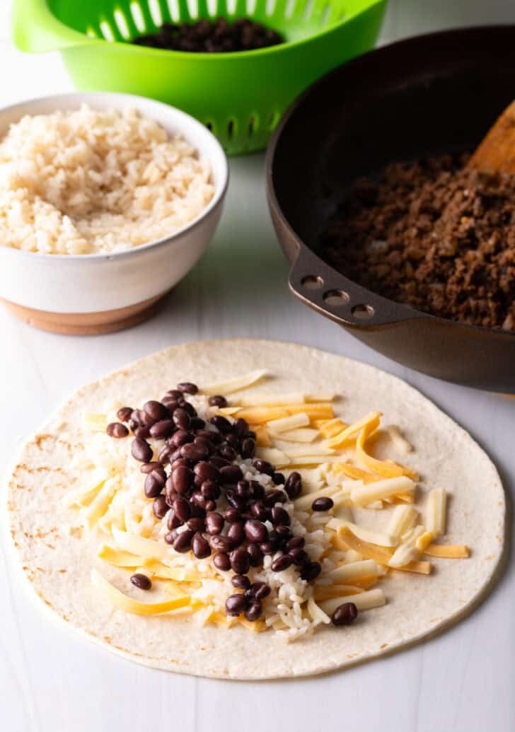 Open-faced flour burrito with shredded cheese, beans, and ground beef.