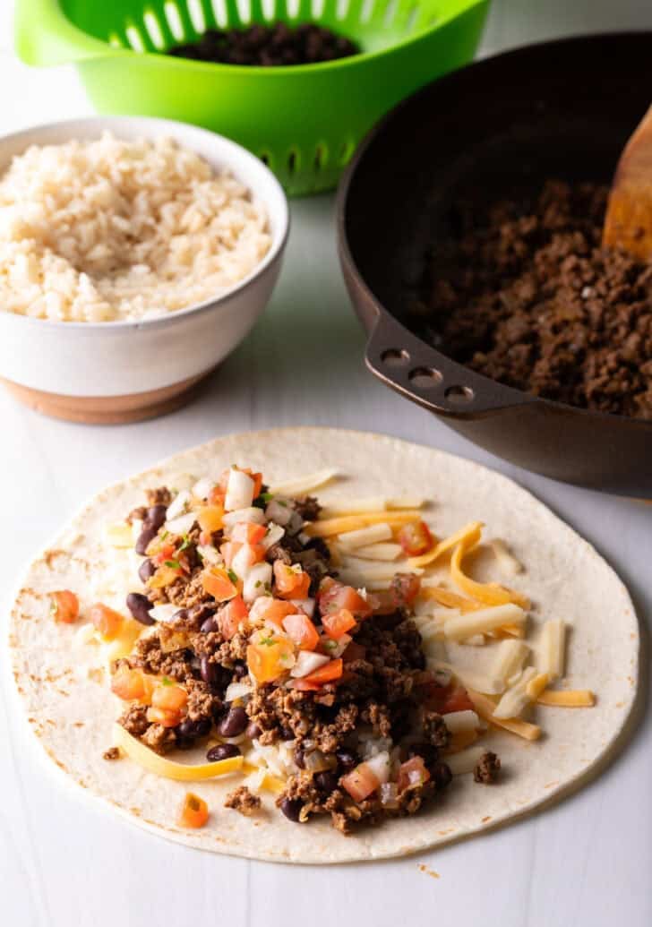 Open-faced flour burrito with shredded cheese, beans, and ground beef.