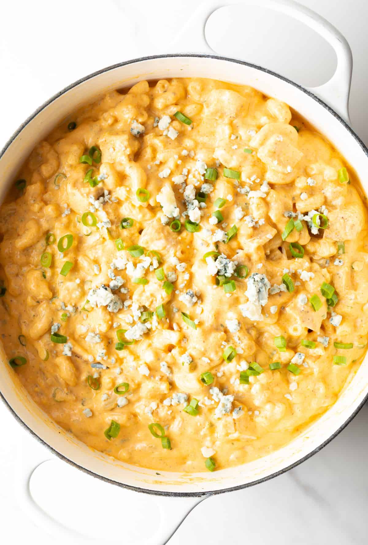 Top down view of a large white pot of buffalo chicken macaroni and cheese.