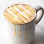 White mug filled with caramel macchiato and caramel drizzle.