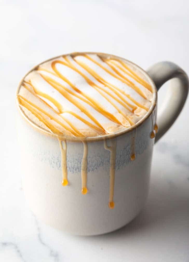 White mug filled with caramel macchiato and caramel drizzle.