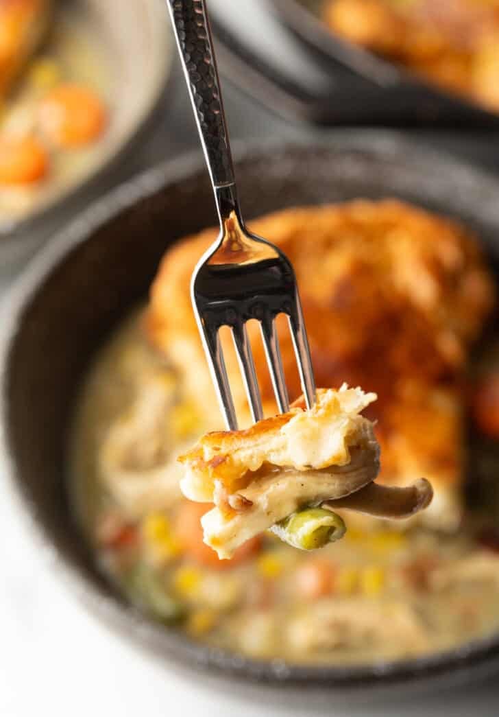 Fork holding a bite of chicken pot pie to camera.