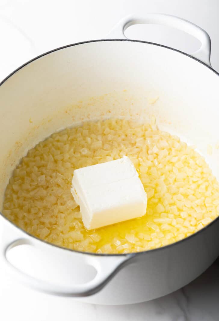 Chunk of butter in a pan with corn.