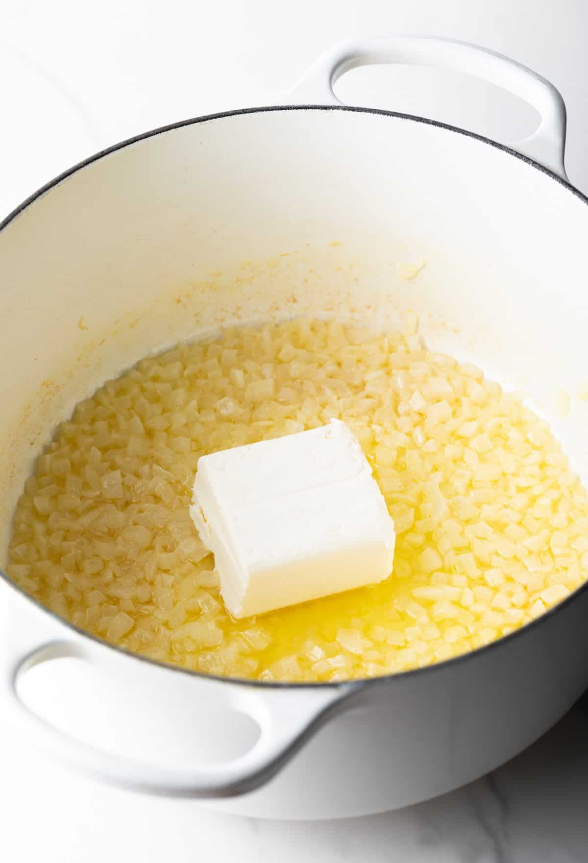Chunk of butter in a pan with corn.
