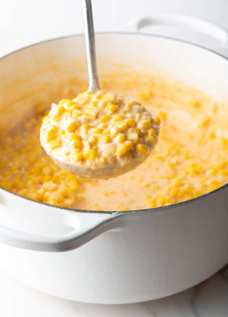 Ladleful of cream corn held to camera.