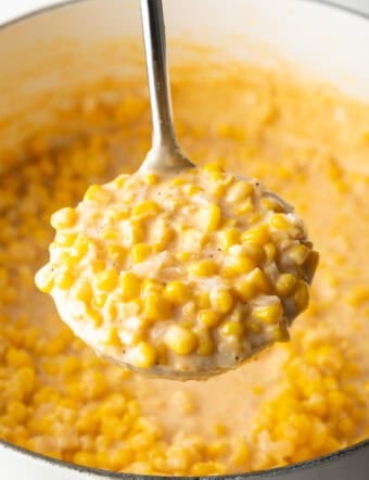 Ladleful of cream corn held to camera.