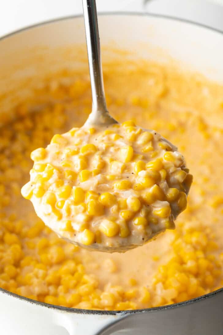 Ladleful of cream corn held to camera.