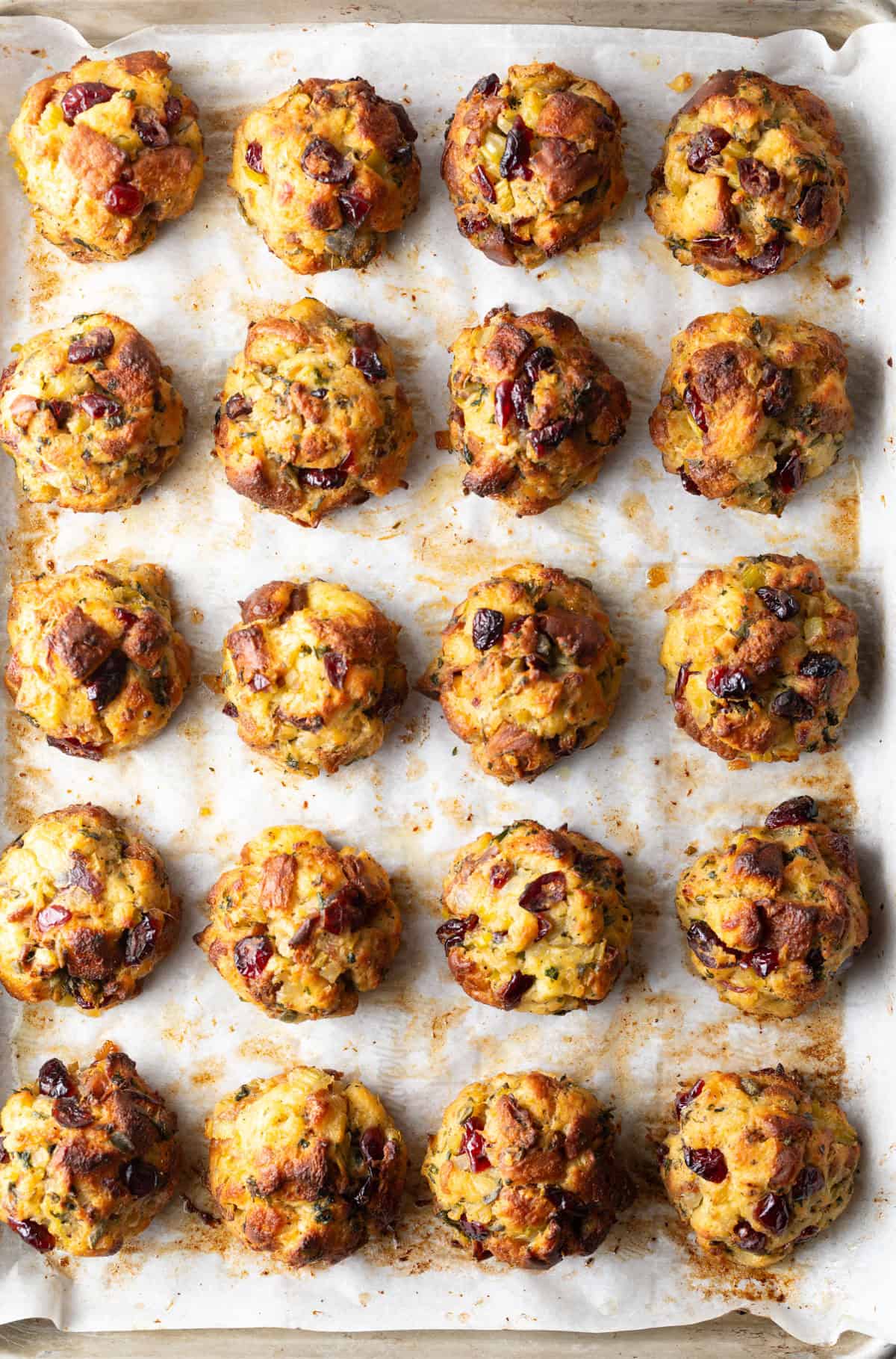 Top down view of 20 stuffing balls in rows on a baking sheet.