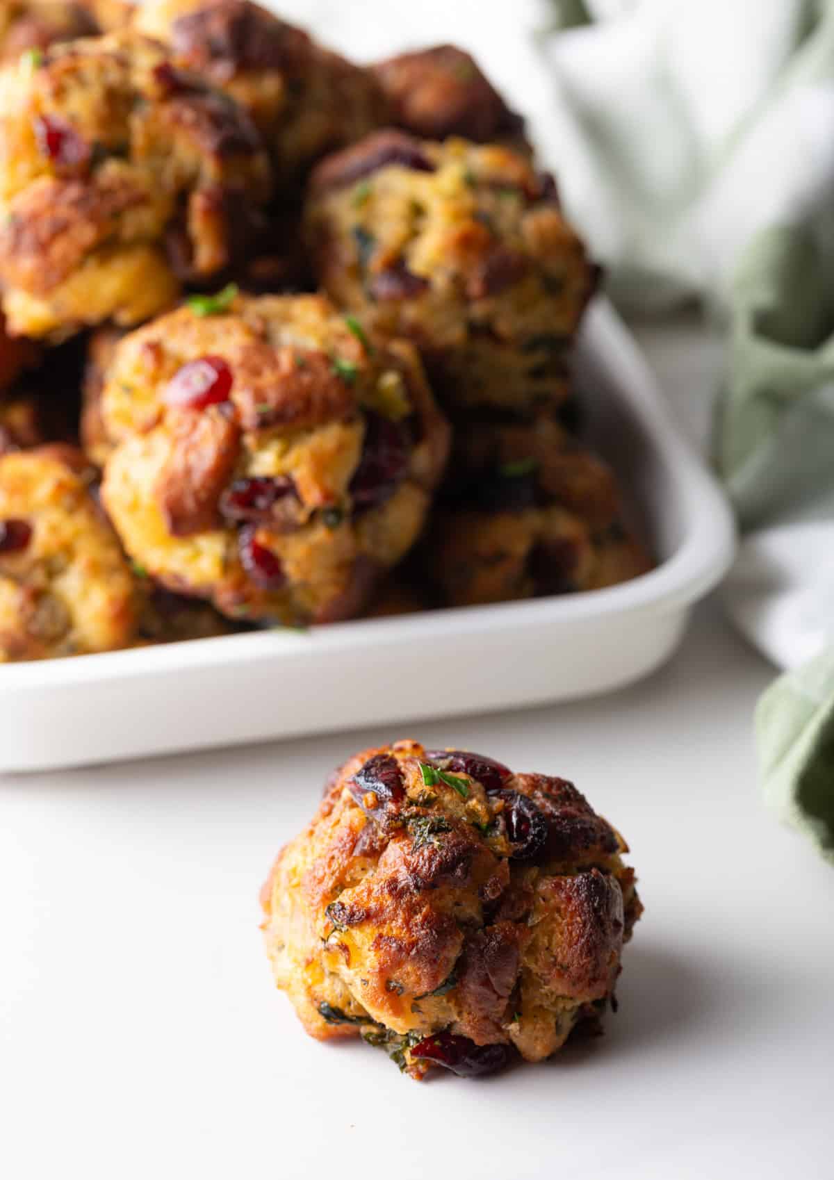 A single stuffing ball on a white counter with plateful of balls in the background.