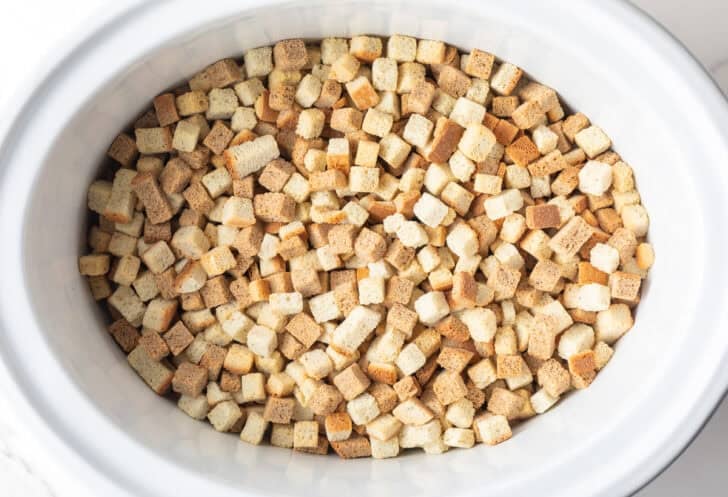 Dried bread cubes in a white crock pot.