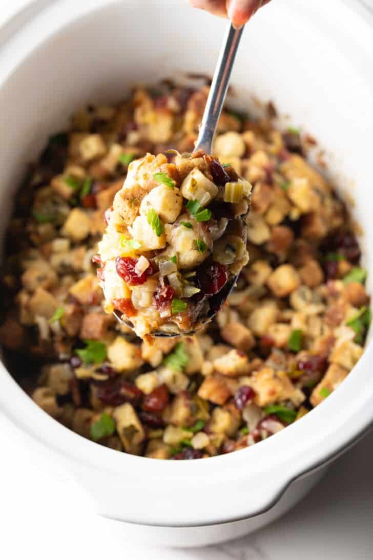 A scoop of crock pot stuffing being held with a metal spoon.