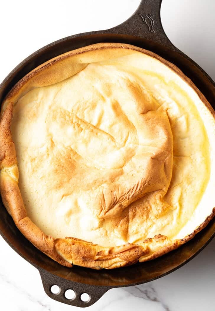 Top down view of a baked Dutch baby in a cast iron skillet.