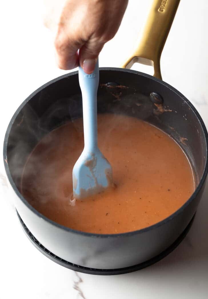 Easy brown gravy recipe being stirred by a spatula in a black pot.