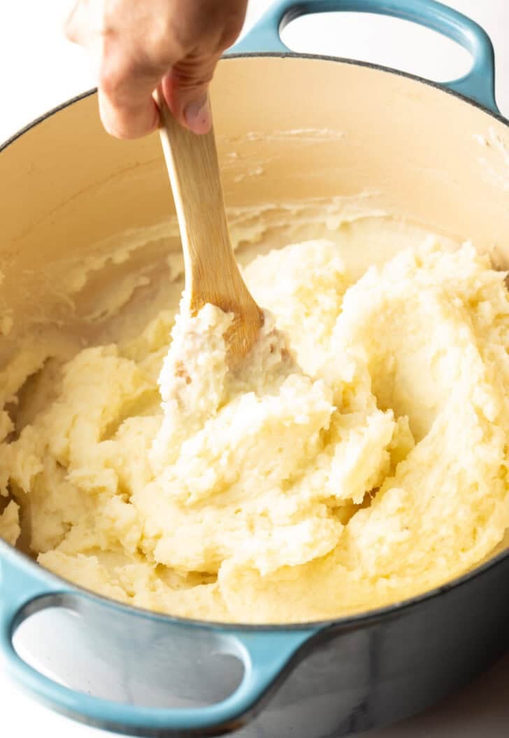 A wooden spoon stirring easy mashed potatoes.