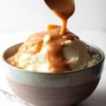 Easy mashed potatoes and gravy with homemade brown gravy being spooned over the mashed potatoes.