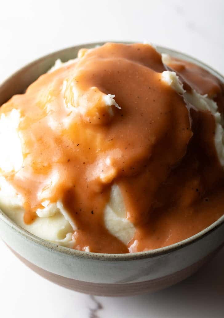 Bowl of mashed potatoes with homemade gravy on top.
