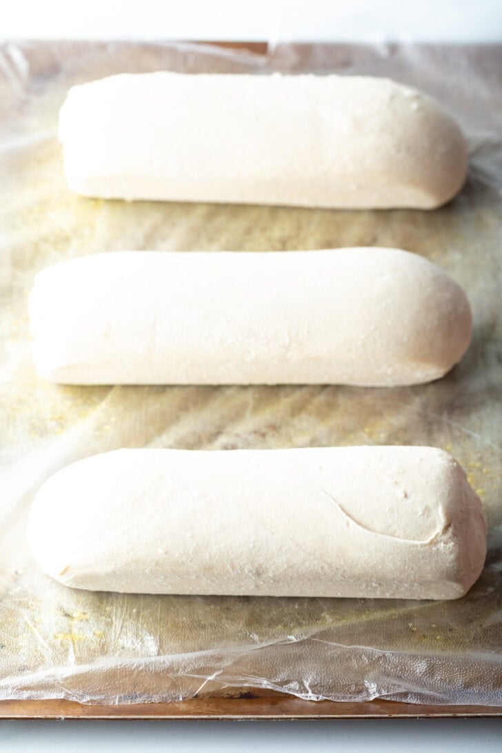 Three loaves of frozen bread dough on a baking sheet.