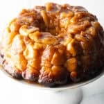 Monkey bread baked in a bundt pan, plated on a white cake stand.