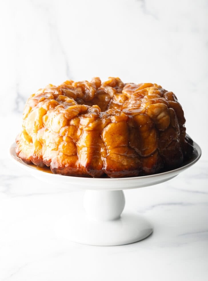 Monkey bread baked in a bundt pan, plated on a white cake stand.