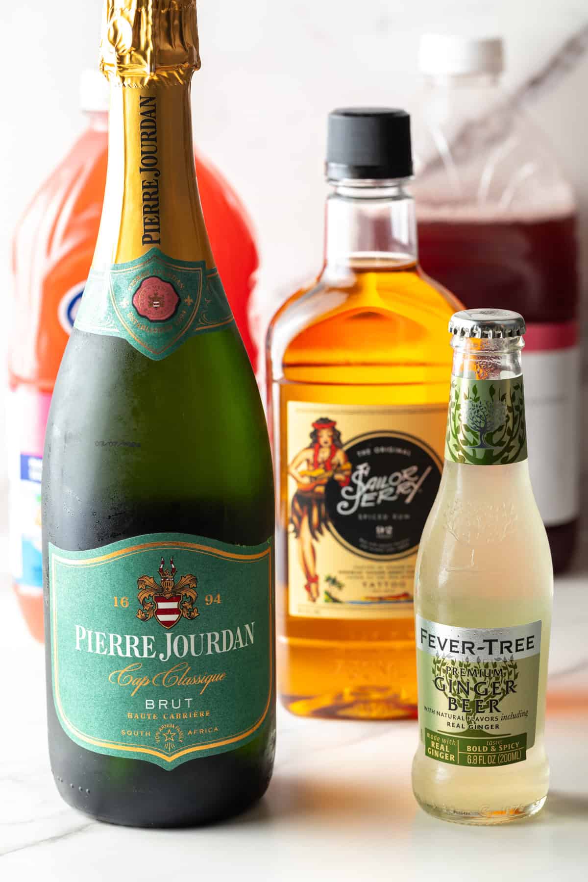 A bottle of champagne, bottle of ginger beer, and bottle of spiced rum.