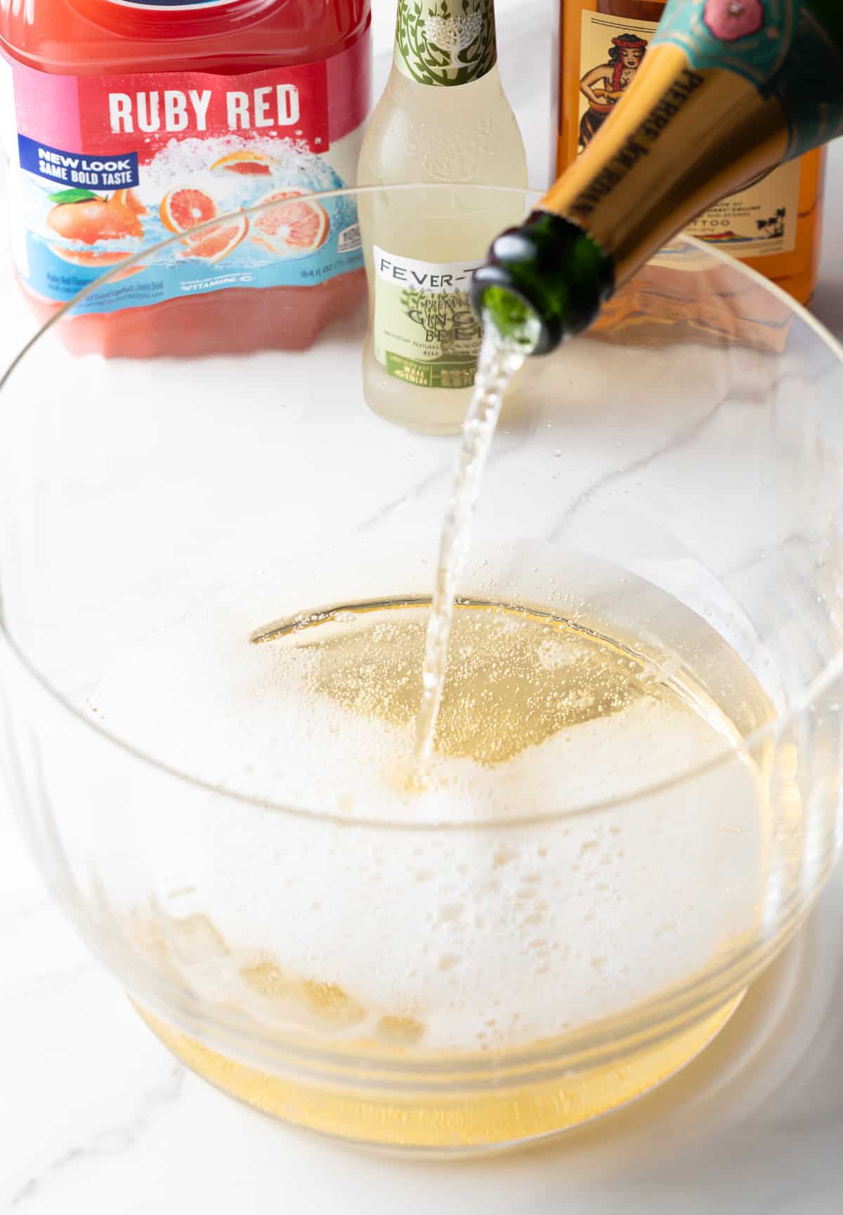 Pouring champagne into a large glass bowl.