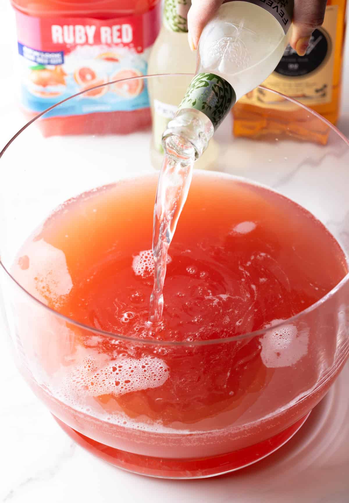 Pouring ginger beer into a large glass bowl.