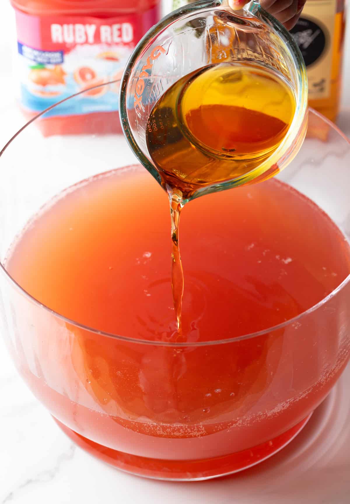Pour dark liquor into a large glass bowl of pink punch.