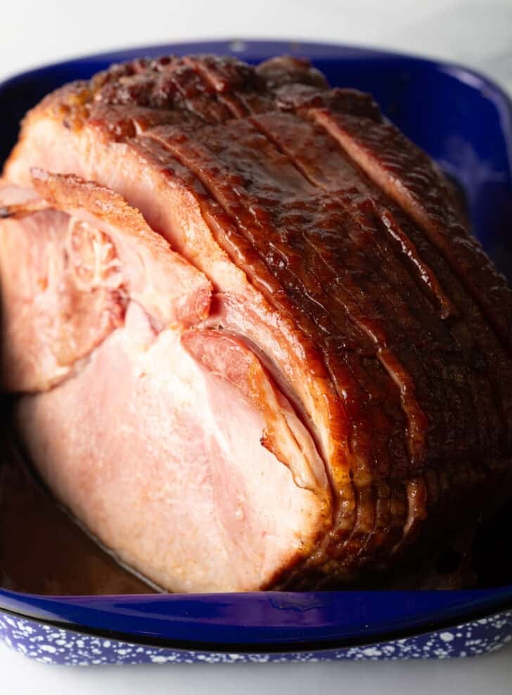 A cooked spiral ham in a blue and white speckled roasting pan.