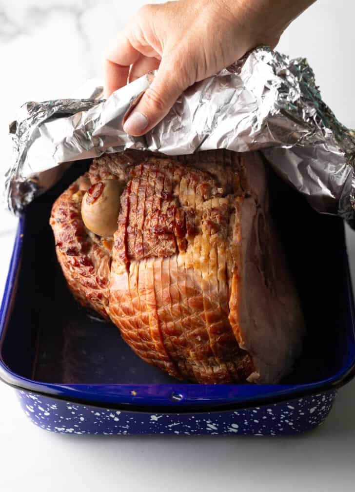 Covering a spiral cam in a blue and white speckled roasting pan with foil.