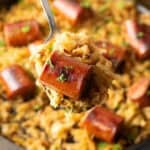 Close view of a piece of cooked sausage on a spoon with sauerkraut.
