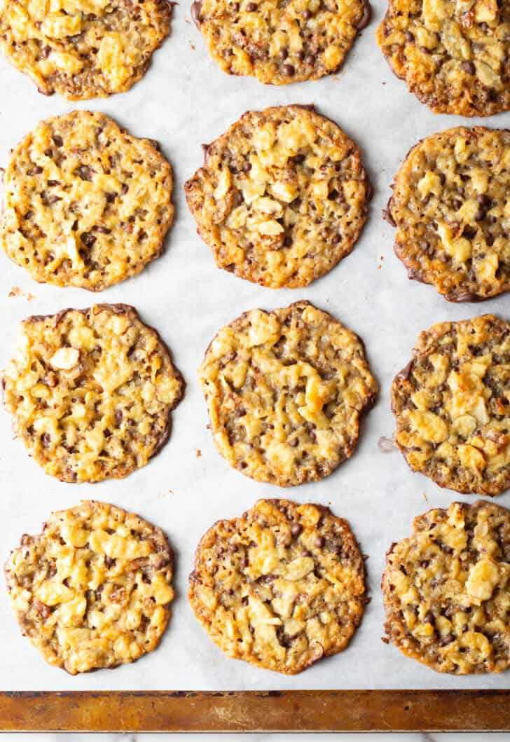 Overhead view of lace cookies lined up in 3 rows on white surface.
