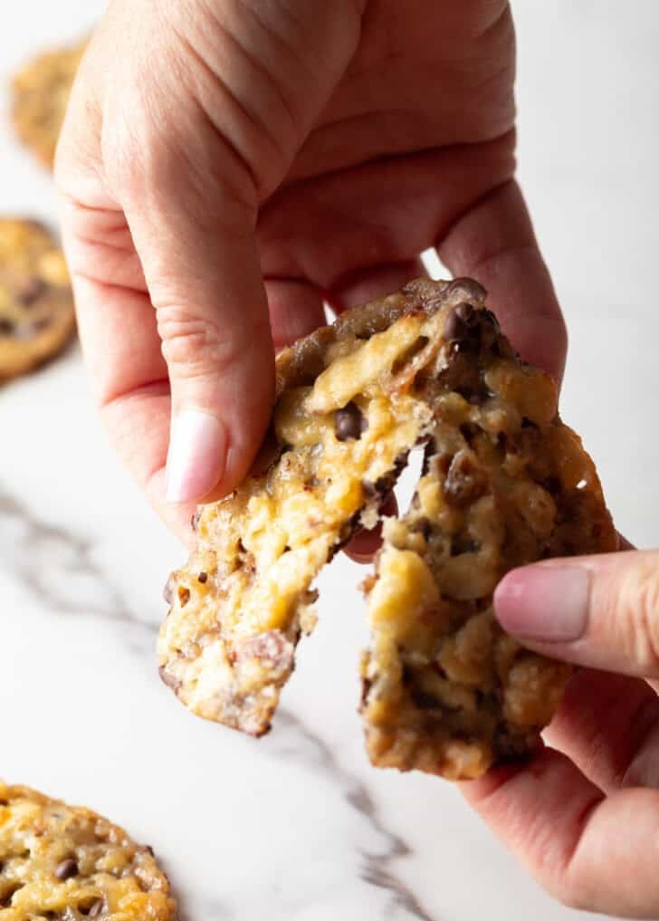 Hands breaking a single Florentine cookie in half.