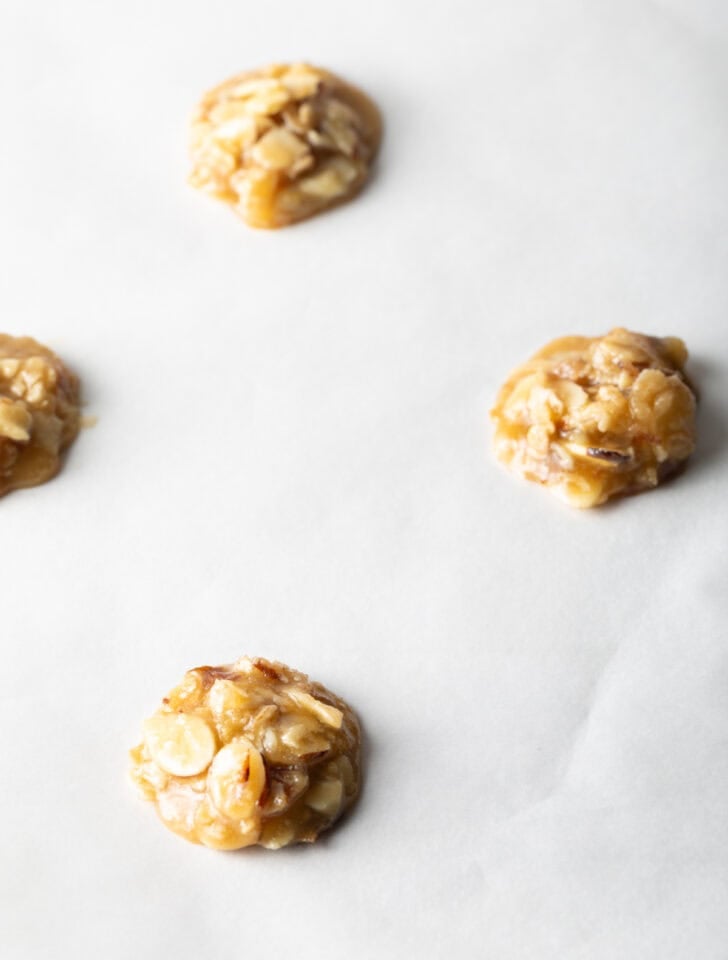 Un-baked lace cookies on white parchment paper ready to go in the oven.