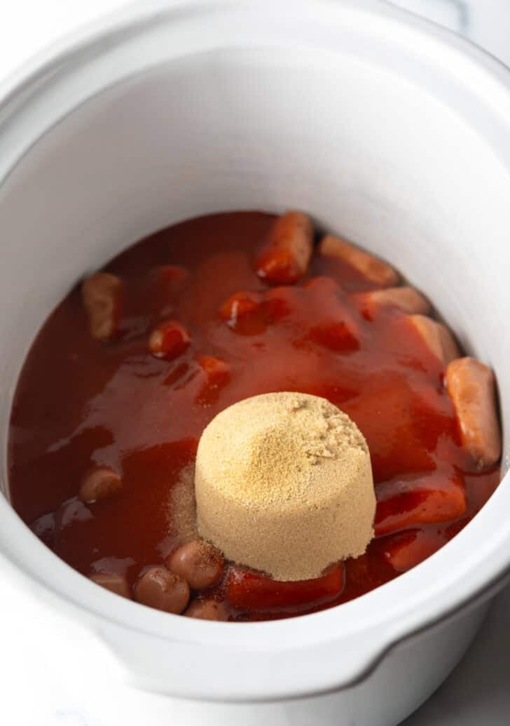 A scoop of brown sugar added to the slow cooker with smokies and barbecue sauce.