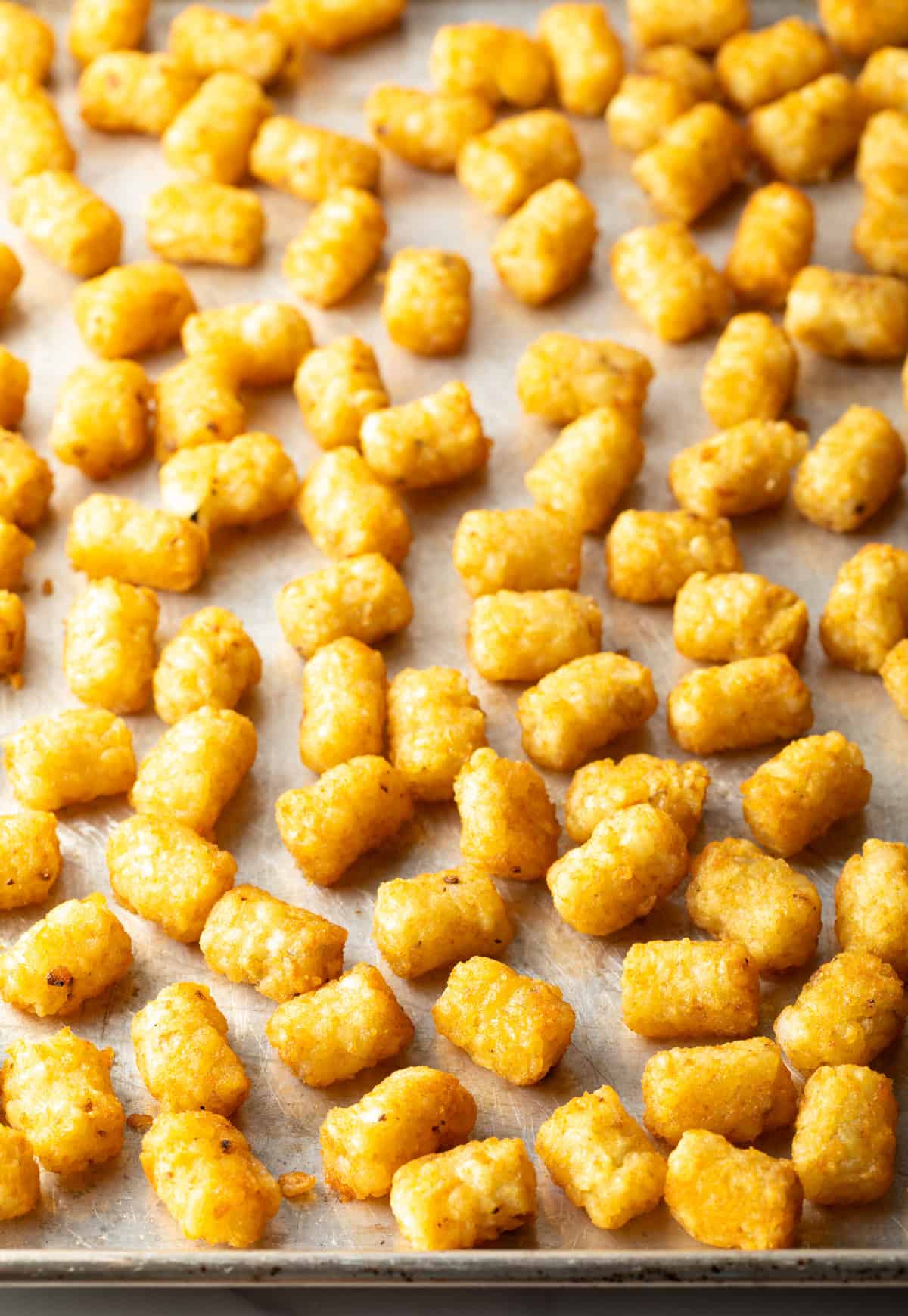 A baking sheet filled with crispy baked tater tots.