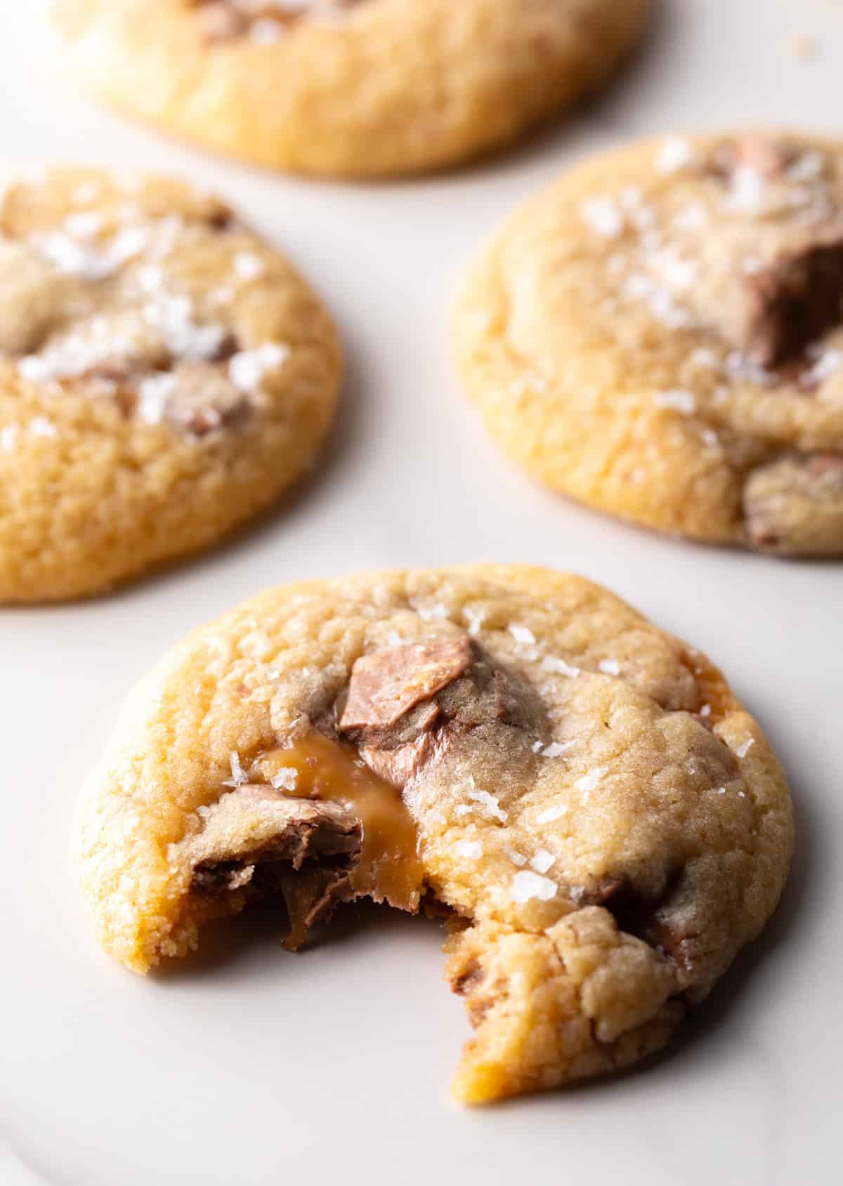 A Milky Way cookie on white surface with a bite taken out of it.