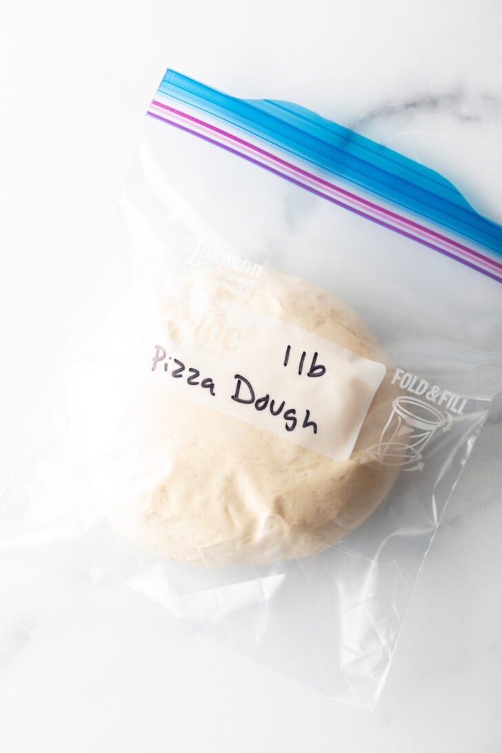 Ball of homemade pizza dough in a plastic Ziploc bag.