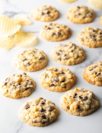 Overhead view of potato chip cookies on marble surface next to potato chips.