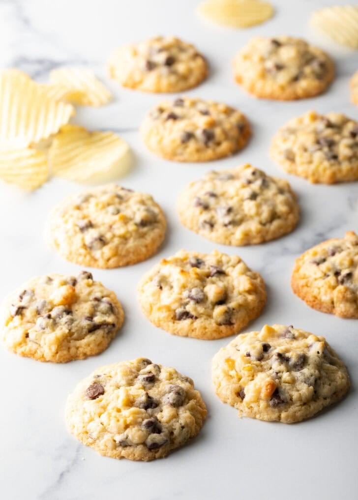 Overhead view of potato chip cookies on marble surface next to potato chips.