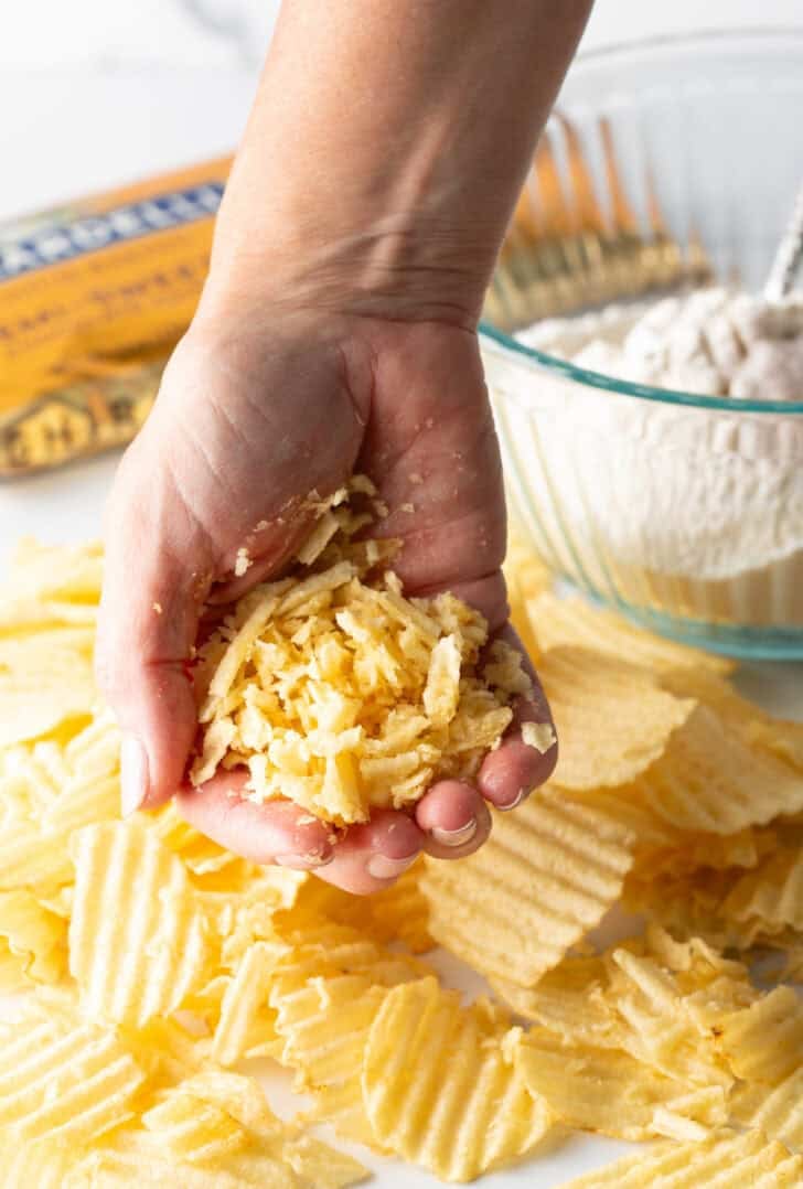 Hand holding crushed up potato chips.
