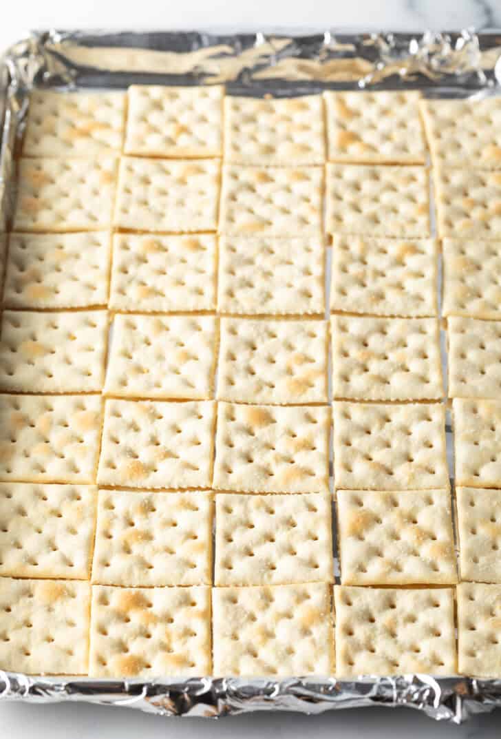 A baking pan covered with rows of saltine crackers.