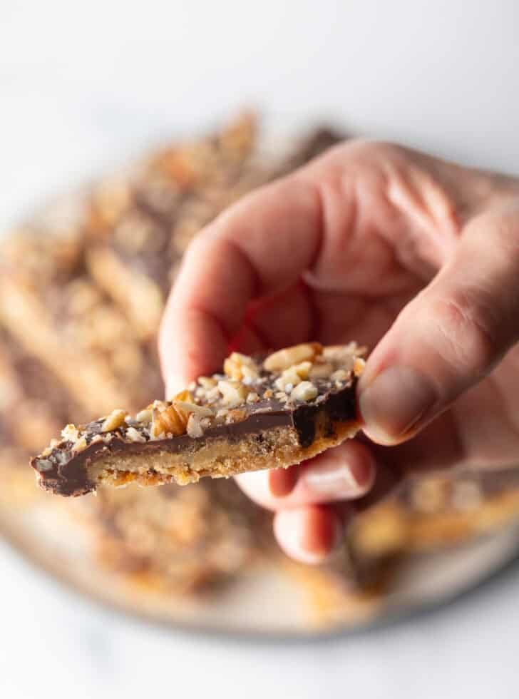 Hand holding a piece of saltine toffee aka Christmas crack.