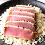 Six slices of seared ahi tuna on a bed of white rice.