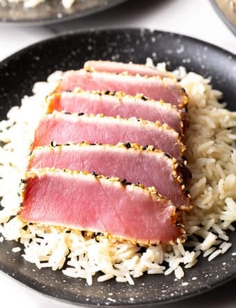 Six slices of seared ahi tuna on a bed of white rice.