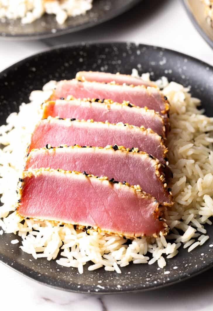 Six slices of seared ahi tuna on a bed of white rice.