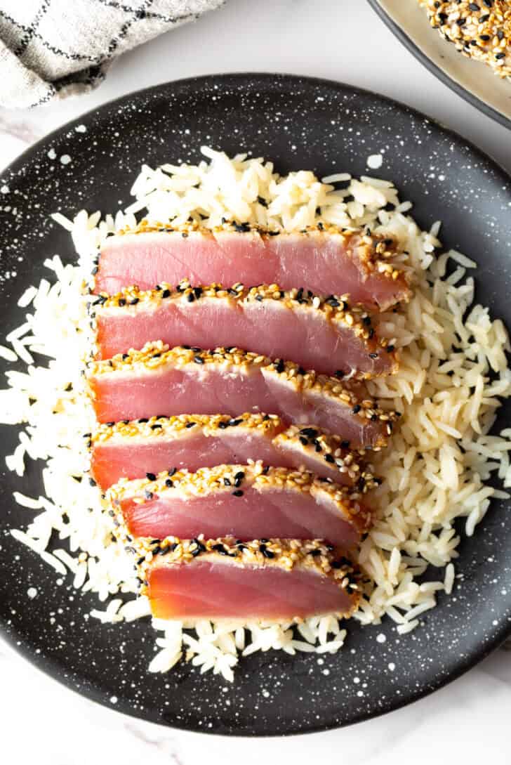 Top down view of six slices of seared ahi tuna on a bed of white rice.