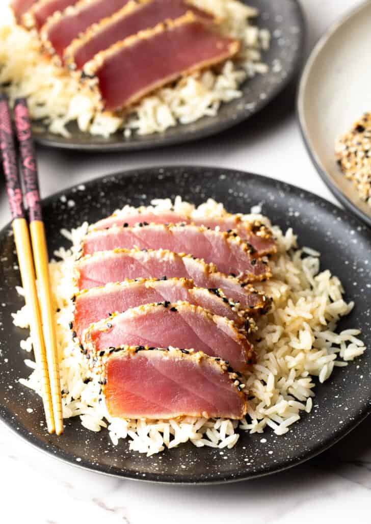 Top down view of six slices of seared ahi tuna on a bed of white rice.