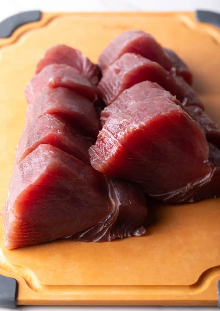 Slices of raw ahi tuna on a cutting board.