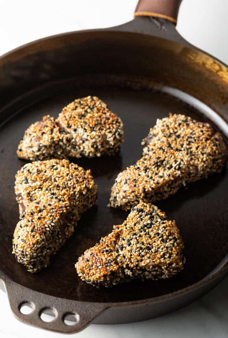4 crusted yellowfin tuna steaks in a cast iron pan.